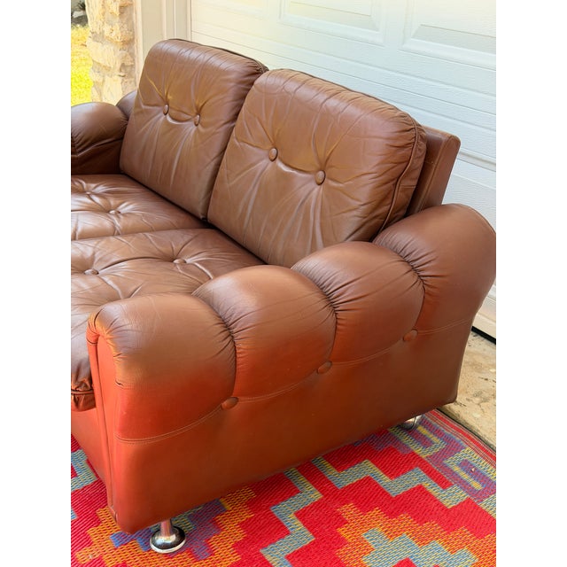 A wonderfully comfortable vintage low two-seater sofa upholstered in warm cognac-brown leather. This piece has a relaxed,...