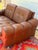 A wonderfully comfortable vintage low two-seater sofa upholstered in warm cognac-brown leather. This piece has a relaxed,...