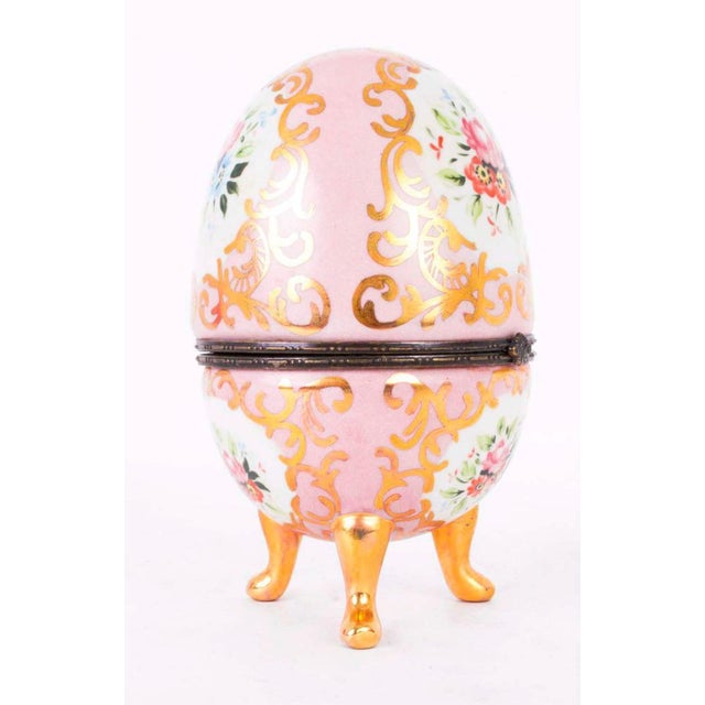 This is a stunning hand painted rose pink porcelain egg with hand painted floral decoration, applied gilding and ormolu...