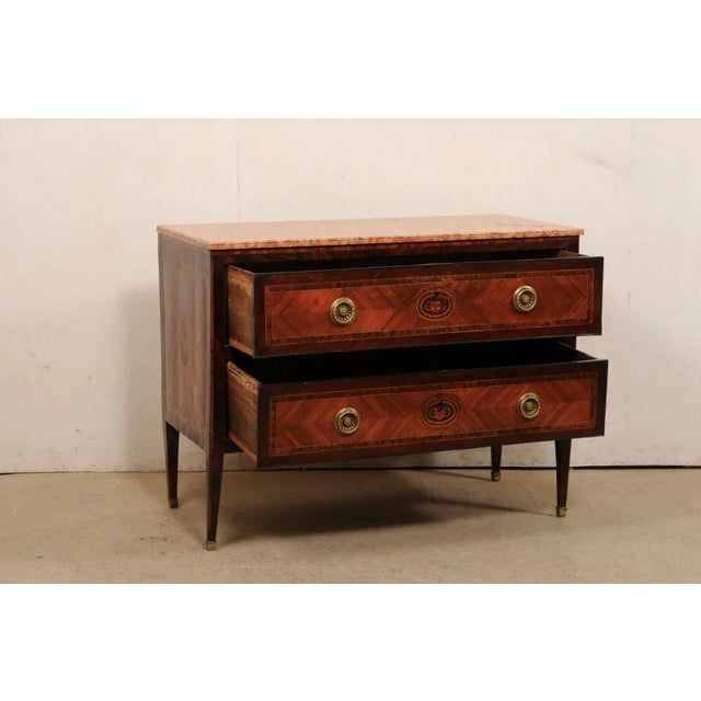 An Italian raised two-drawer chest, with its original marble top, from the late 18th century. This antique chest from...