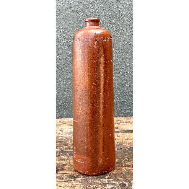 Vintage De Kuyper pottery bottle with a cylindrical form, warm reddish-brown finish, and a softly aged natural patina....