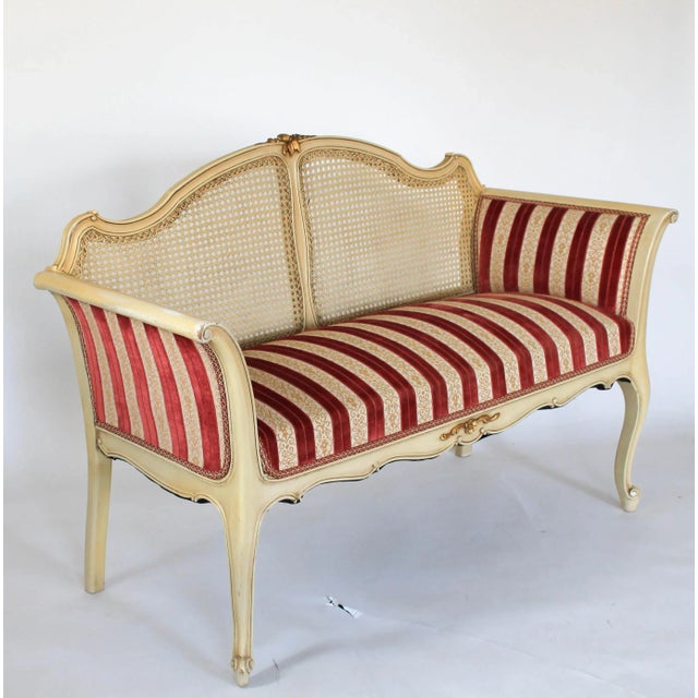 Vintage Louis XV style curved cane-back settee or loveseat with scrolled splayed arms and front escargot feet, circa...