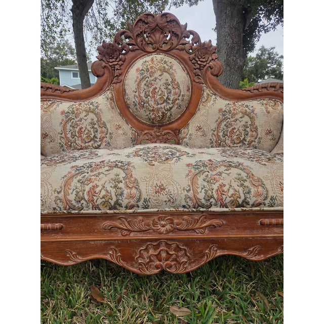 This vintage carved walnut settee is a striking example of mid-20th-century European revival craftsmanship, drawing...