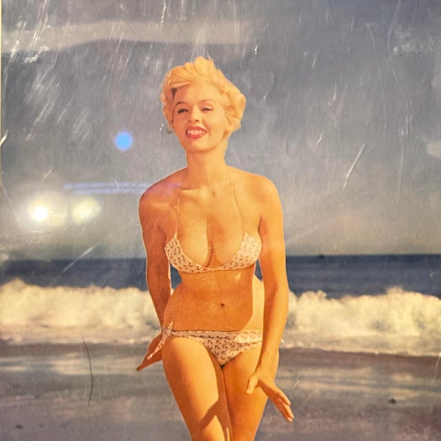 A vintage mid-century pin-up photographic print featuring a classic beach glamour pose, emblematic of 1950s American pop...