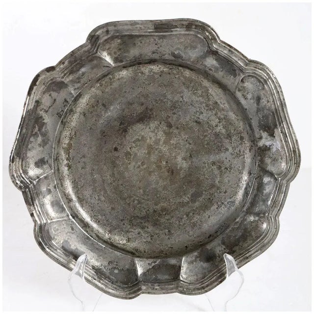 DETAILS An antique European plate of round form with a wide rim and wavy, serpentine reeded edge. Ownership initials (on...