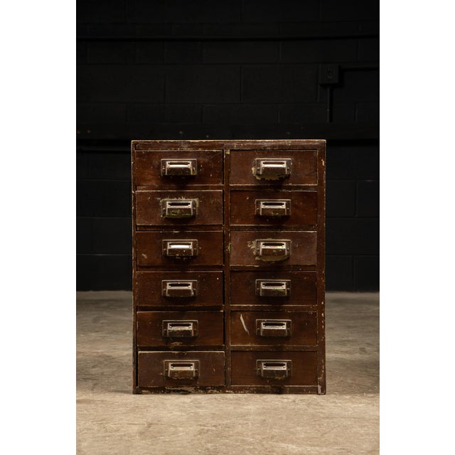 Wooden industrial cabinet. This piece features solid oak construction and original cast iron handles. Drawers (x12): 7.5"...