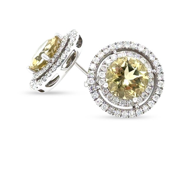 A striking pair of 14ct white gold stud earrings featuring vibrant heliodor gemstones framed by a double halo of sparkling...