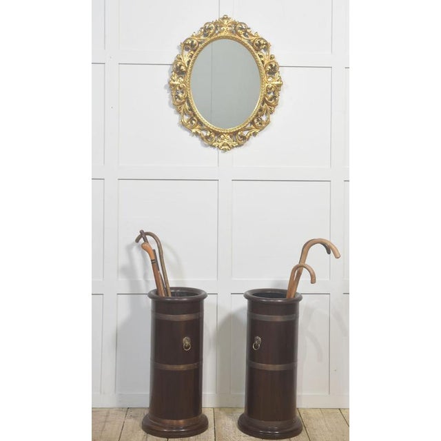 Pair of 19th-century mahogany umbrella stands, each of cylindrical form and finished in a deep, warm patina. The bodies...