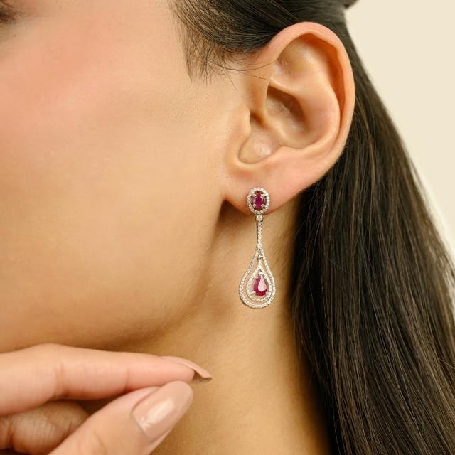 These contemporary Art Deco–inspired drop earrings features 4 pear and oval cut rubies totaling 2.06 carats set in rich...