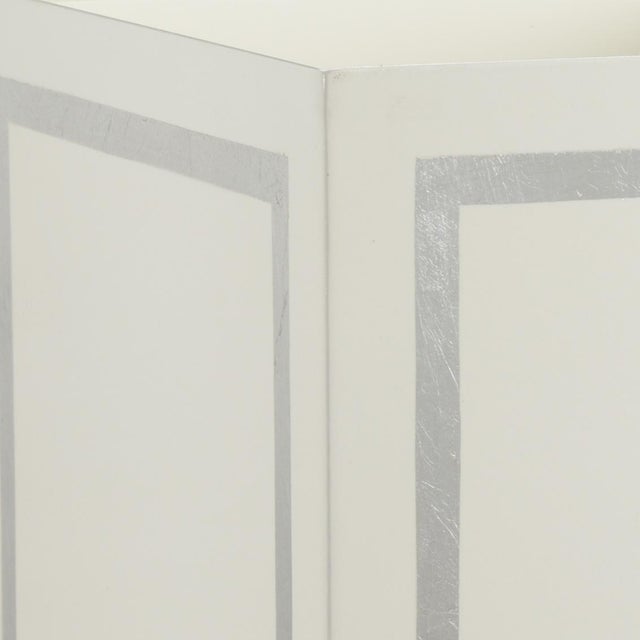 Cream metal wastebasket with metallic silver trim, designed by Claire Bell.