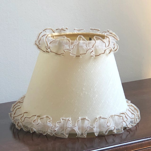 Offering a wonderfully preserved 1950s clip-on lamp shade in a soft ivory and rims embellished with the cutest little...