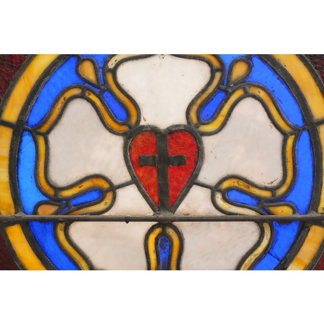 Antique rectangular church window with textured stained glass panels of yellow, amber, brown, and blue colors. The outside...