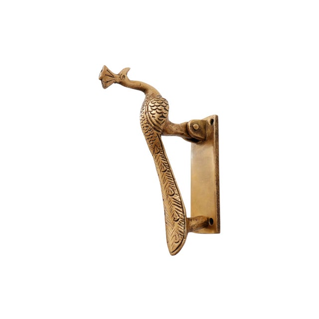 A brass door knocker shaped like a peacock. Cast with prominent crest feathers and a long tail, finished with line details...