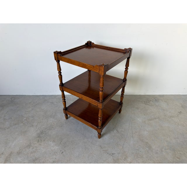 A charming vintage English three-tier side table crafted with elegantly turned legs and a raised gallery top. Its compact...