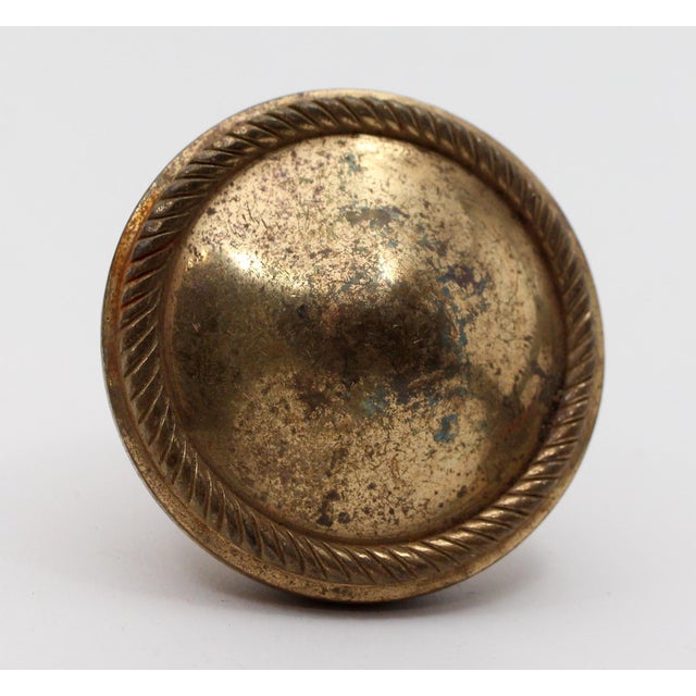 Concentric braided design entry door knob. Made of brass in a polished finish. The manufacturer and date of creation is...