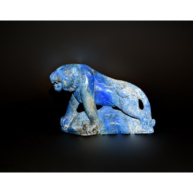 A striking hand-carved tiger sculpture in natural lapis lazuli, with intense coloration and natural marbling creating a...