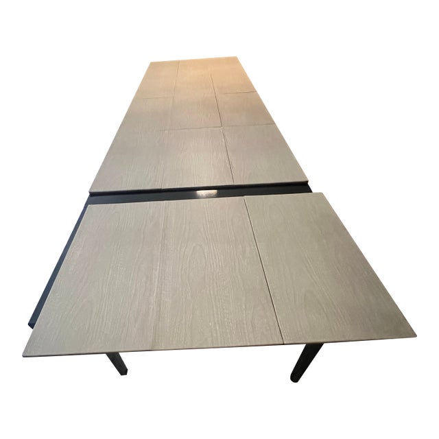 Elegant mid-century modern extendable dining table featuring a sleek high-gloss black lacquer finish and a sculptural...