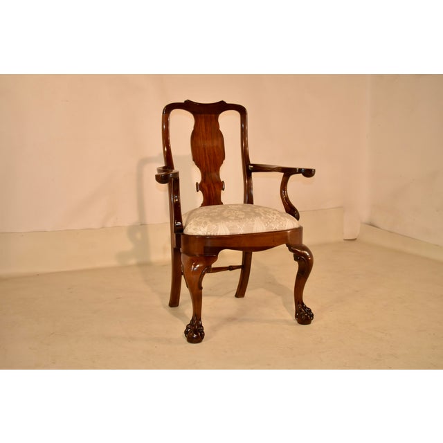 18th century mahogany Queen Anne arm chair from England. The top rail on the back has a central scroll, continuing in...