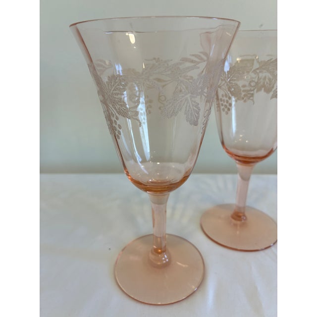 A charming set of four vintage pink wine glasses featuring an etched grape and vine motif. The soft blush tone paired with...