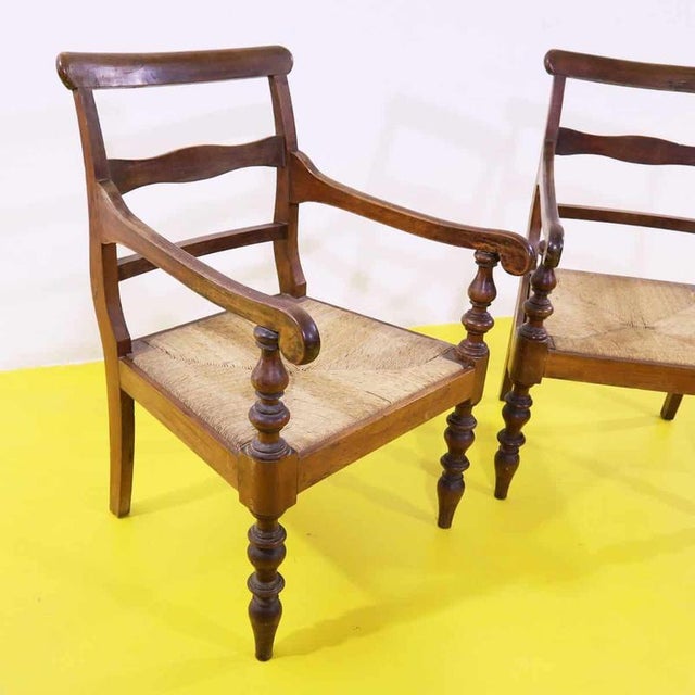 Pair of vintage wooden armchairs featuring woven seats.