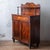 An English mahogany chiffonier with an upper shelf, shaped gallery back, and one drawer with a concealed spring-release...