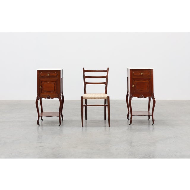 A sophisticated pair of French Louis XV style nightstands from around 1900, crafted in richly toned walnut and topped with...