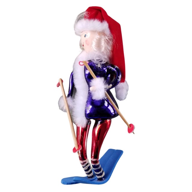 Hand blown and hand painted hanging Christmas ornament. A hand painted snow skier with wind swept hair wears a vibrant...