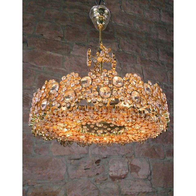 Glamorous crystal chandelier made of a 24-carat gold-plated brass frame with crystal prisms and gilt brass rings. The...
