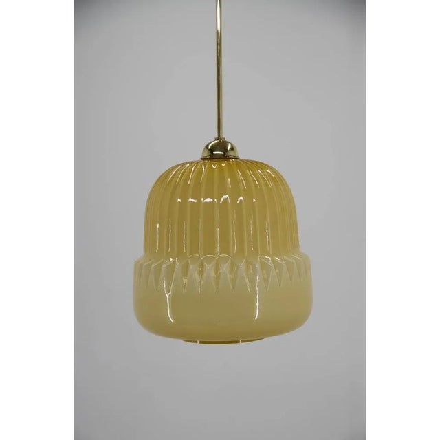 Dark yellow midcentury pendant made of glass and brass. Glass in good condition with one little chip on bottom visible on...