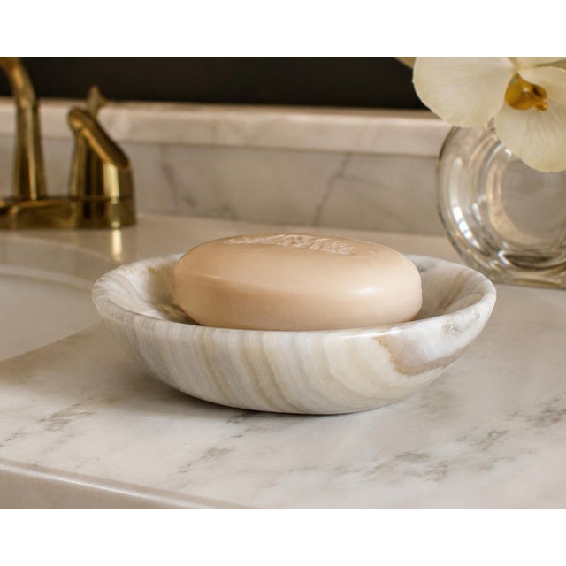 A beautiful hand-carved dish crafted from genuine natural onyx, showcasing elegant layers of creamy ivory, soft beige, and...