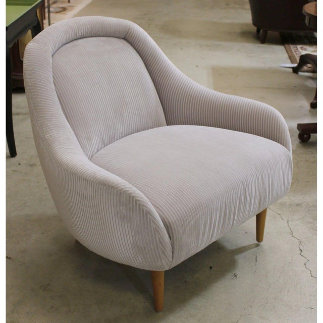 This compact accent chair features a rounded back and gently curved arms that create a soft, sculptural silhouette. The...