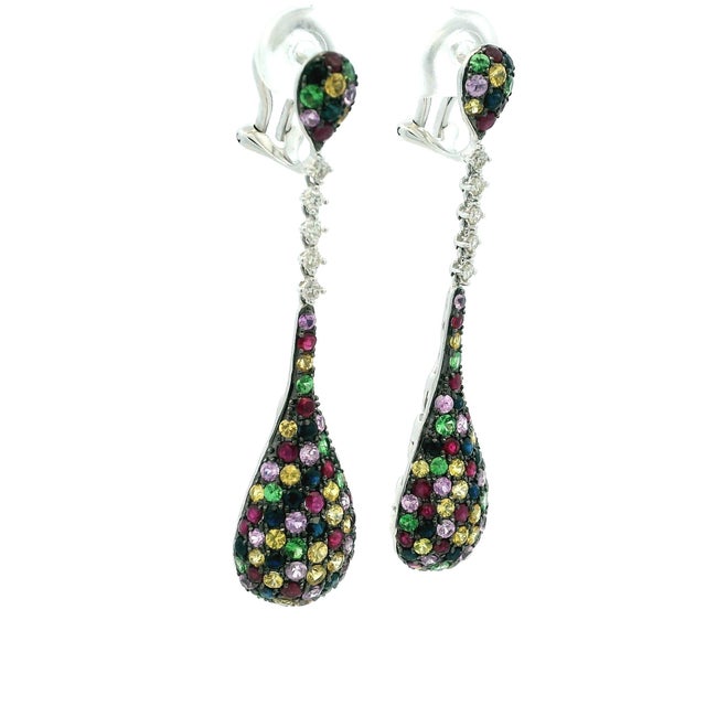 Elegant and colorful Italian 14K white gold drop earrings featuring a vibrant pavé arrangement of mixed sapphires in...