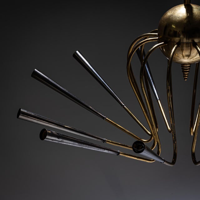 Large-scale Sputnik chandelier in brass featuring twelve angled arms composed of slender rods, radially arranged around a...