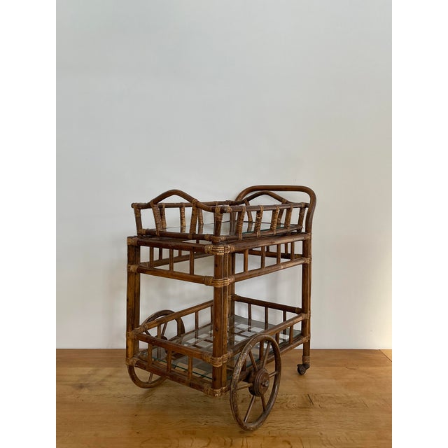 Charming vintage rattan bar cart featuring classic lattice detailing, and two glass shelves for stylish display and...
