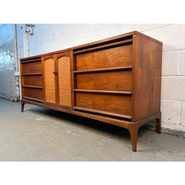 Mid-Century Modern Lane “Rhythm” Walnut Credenza. Crafted in the 1960s by Lane Furniture, this iconic piece showcases the...