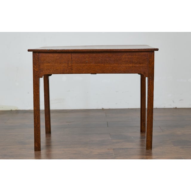 An English Georgian oak table from the 19th century with single drawer and Chippendale style hardware. Elevate any room...