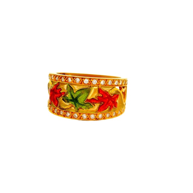 A vibrant ring showcasing a ring of 18k yellow gold. The design features colorful enamel leaves in red and green hues....