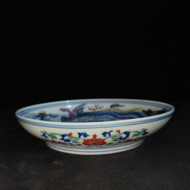 Beautiful Chinese wucai porcelain shallow bowl/plate hand-painted with vibrant dragon and phoenix motifs. A bold red...