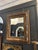 Vintage wall mirror with a richly layered wood frame featuring distressed finish and carved detailing. The frame shows...