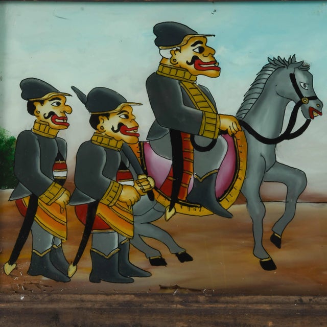This Framed Punakawan Reverse Painting Glass Military Salute is a vibrant and whimsical portrayal of Javanese folk...