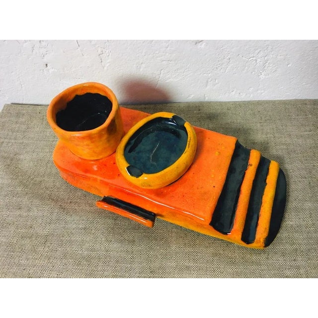 Handcrafted ceramic smoking set by Zsuzsa Heller with bright orange and black glaze, including an ashtray and cigarette...