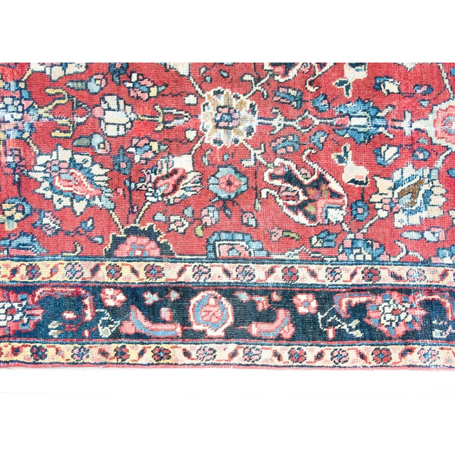 A hand knotted early 20th century Persian Heriz rug with a large-scale floral and leaf patterned field surrounded by a...