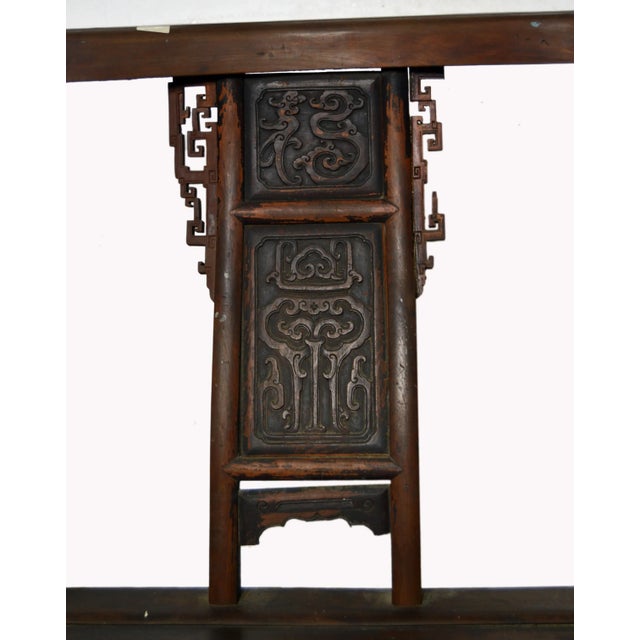 A Chinese hand-carved yumu wood 'Official's Chair' with fretwork and lacquered finish. This Chinese armchair features a...