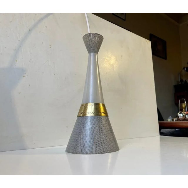 Stylish Diablo shaped ceiling pendant lamp in glass and brass. The glass features hand-engraved patterns derived from the...