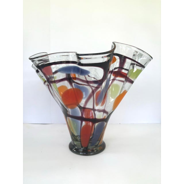 This striking contemporary art glass vase features a dramatic flared form with a deeply ruffled, undulating rim and a...