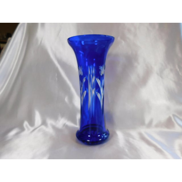This is a blue cut to clear vase with a wider base than the vase and a flared top. It has a flower shaped cut out, three...