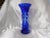 This is a blue cut to clear vase with a wider base than the vase and a flared top. It has a flower shaped cut out, three...