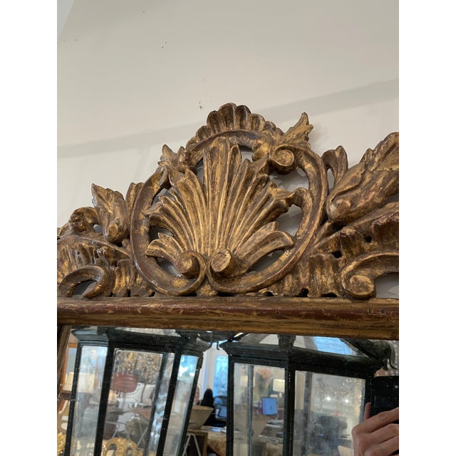 This Rococo giltwood mirror is characterized by its exuberant design and finely carved ornamentation, featuring scrolling...