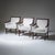 Set of three armchairs, model “Minerva,” with dark-stained wooden frames. The chairs feature slightly flared armrests and...