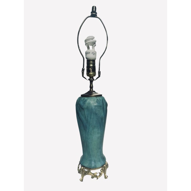 Gorgeous blue-teal pottery ceramic body with gold metal rococo, French inspired. A new white fabric lamp shade is attached.